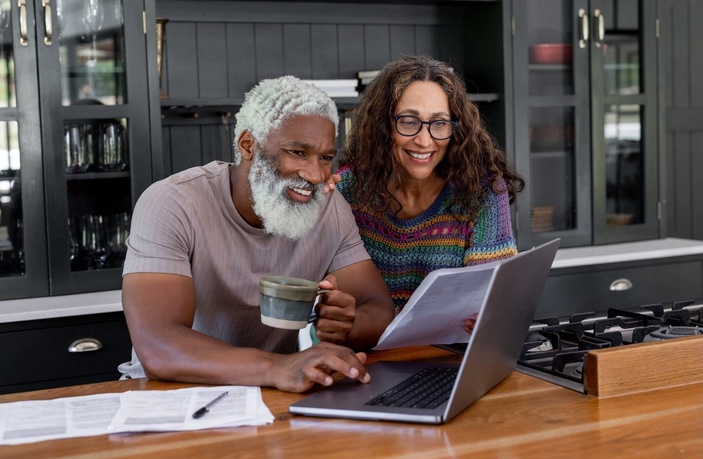 Older couple reviews their 401k plan on a laptop on their kitchen counter
