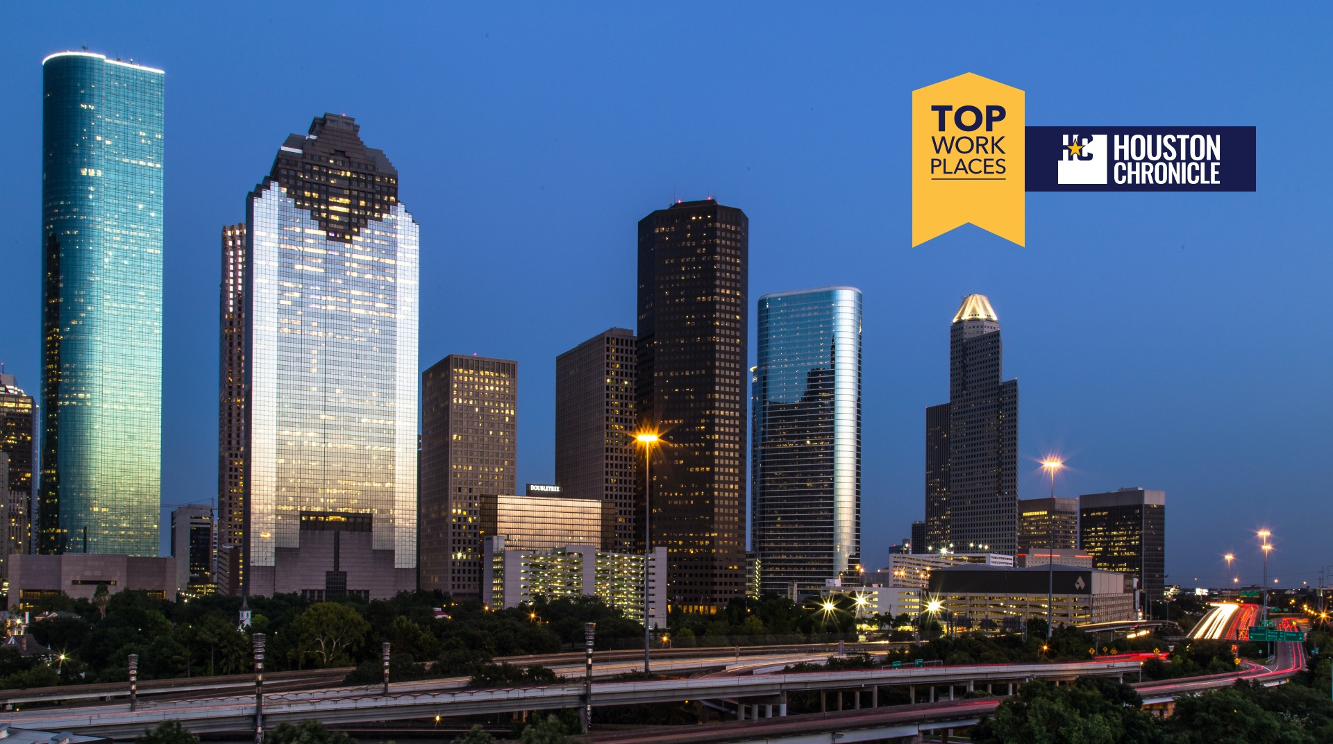 Houston skyline at night with 'Top Workplaces 2023' badge