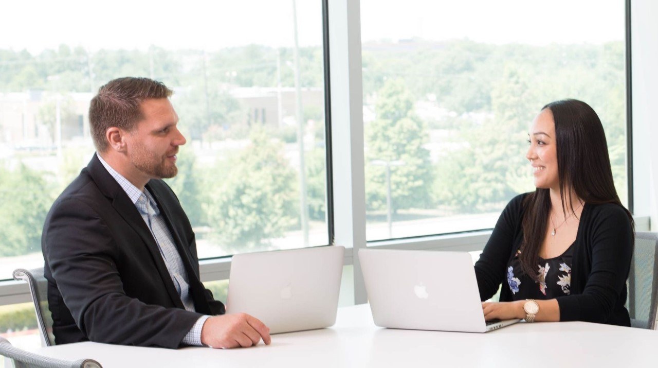 Man and woman in window office having a conversation. Manger utilizing situational leadership techniques with employee.