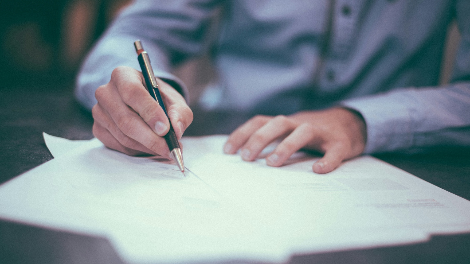 Man sitting at a desk signing paperwork