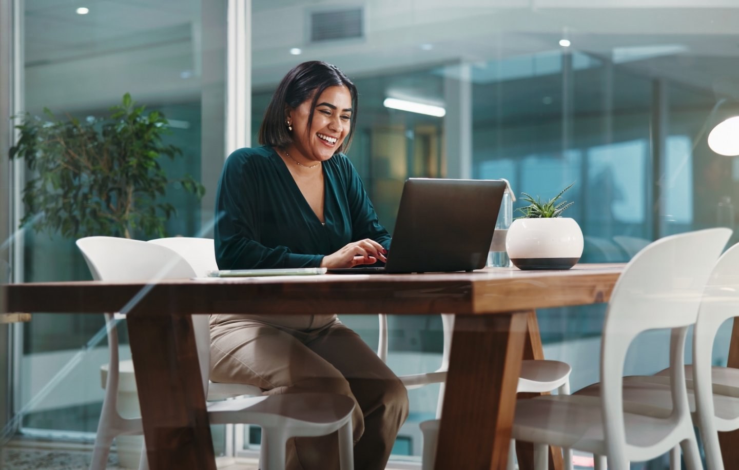 Employee completes benefits enrollment on her laptop in an office communal space.