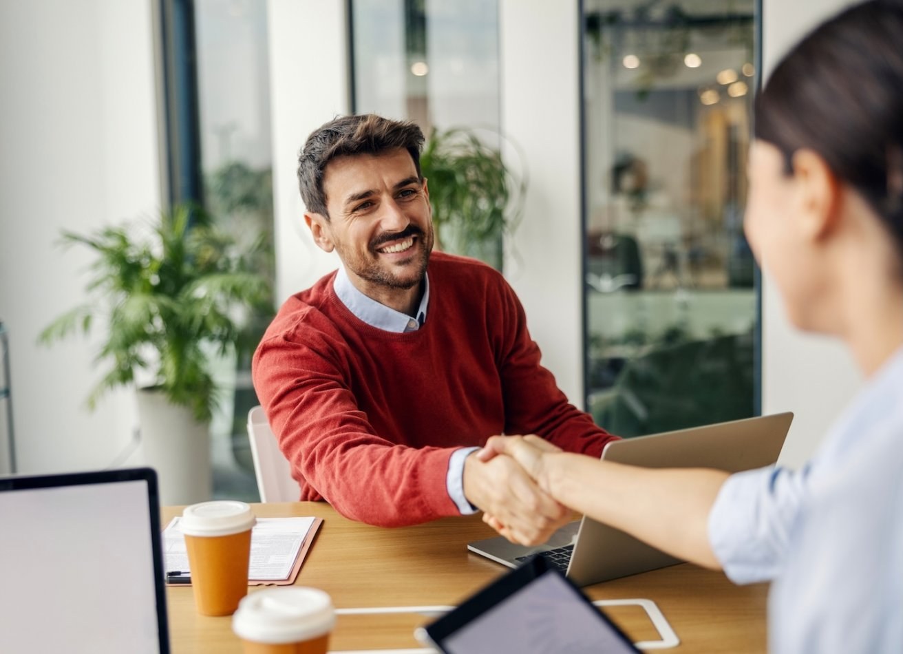 Smiling man shakes hand of female job interviewer