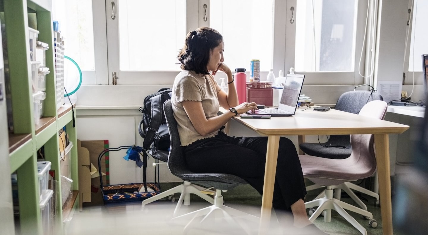 Woman sits in the office of her nonprofit organization researching on her laptop