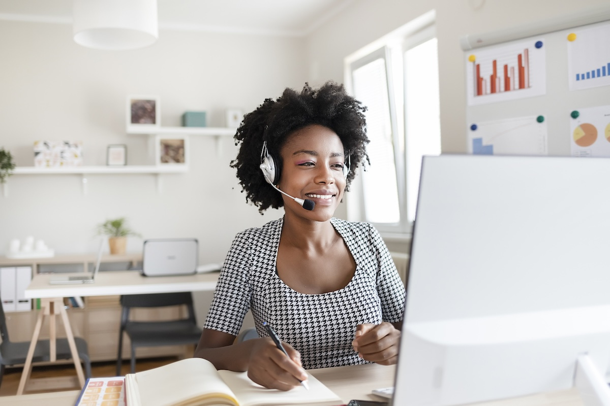 Woman wearing headset works remotely from a desk computer