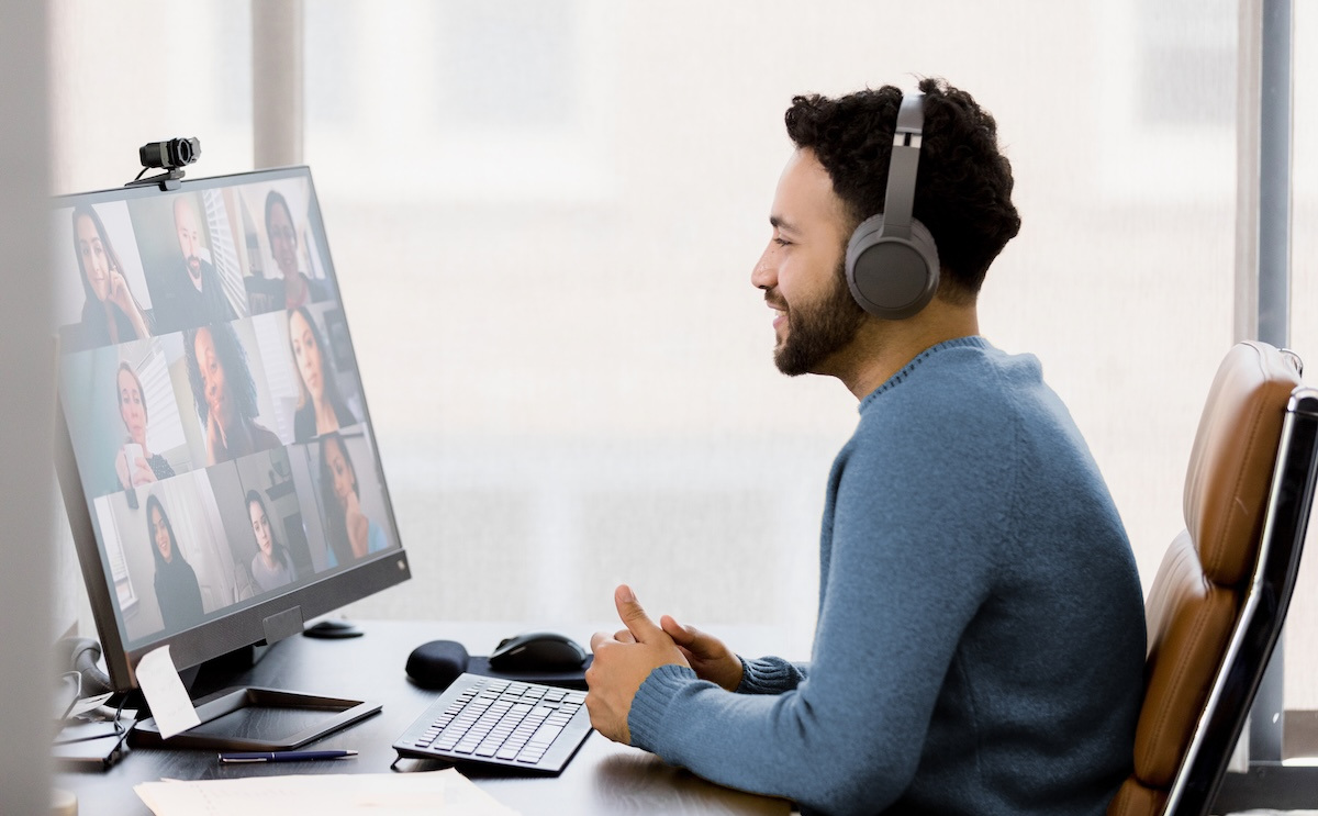 Employee wearing headphones works from home on a video call with colleagues