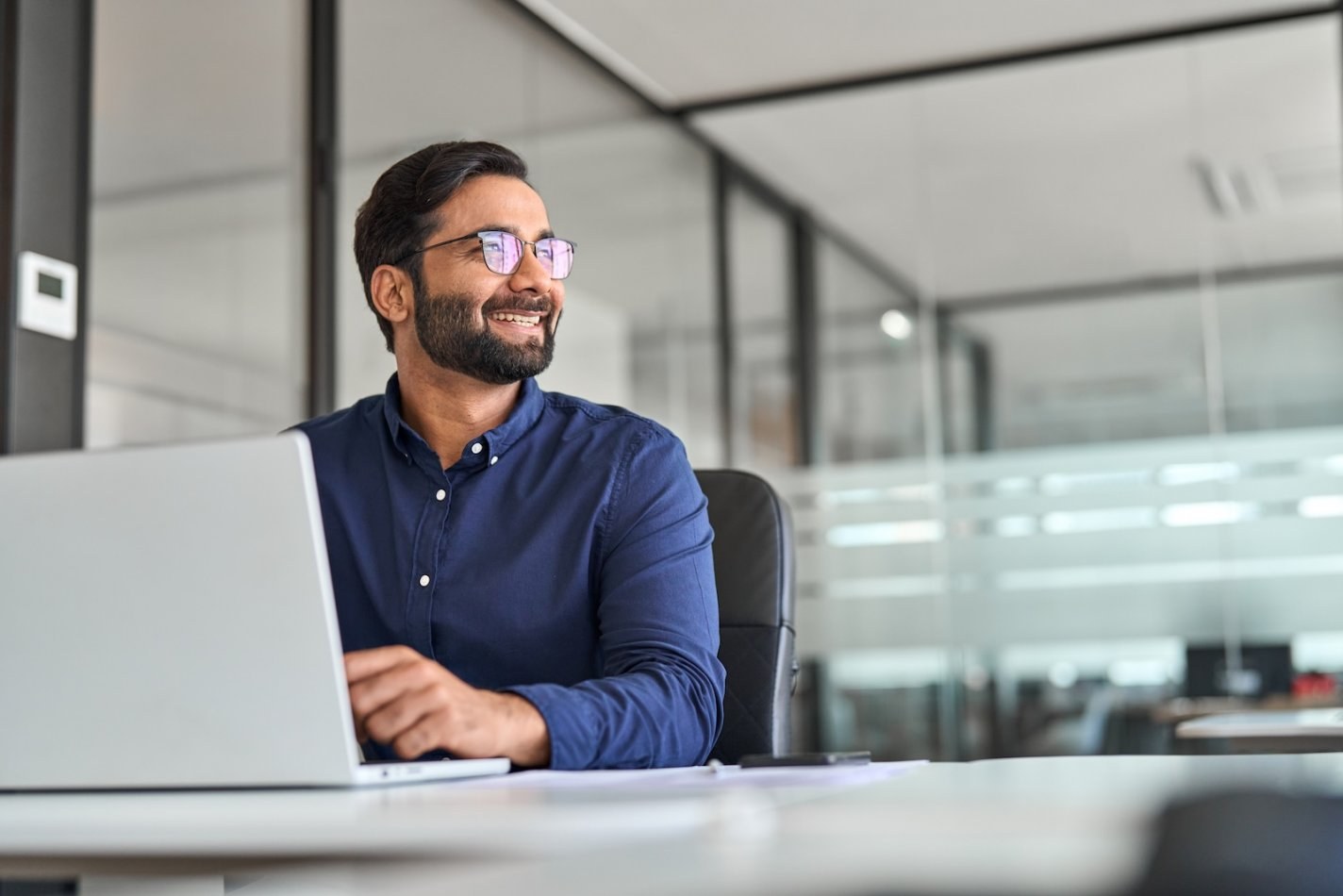 HR manager uses AI tool on his laptop, smiling at coworker