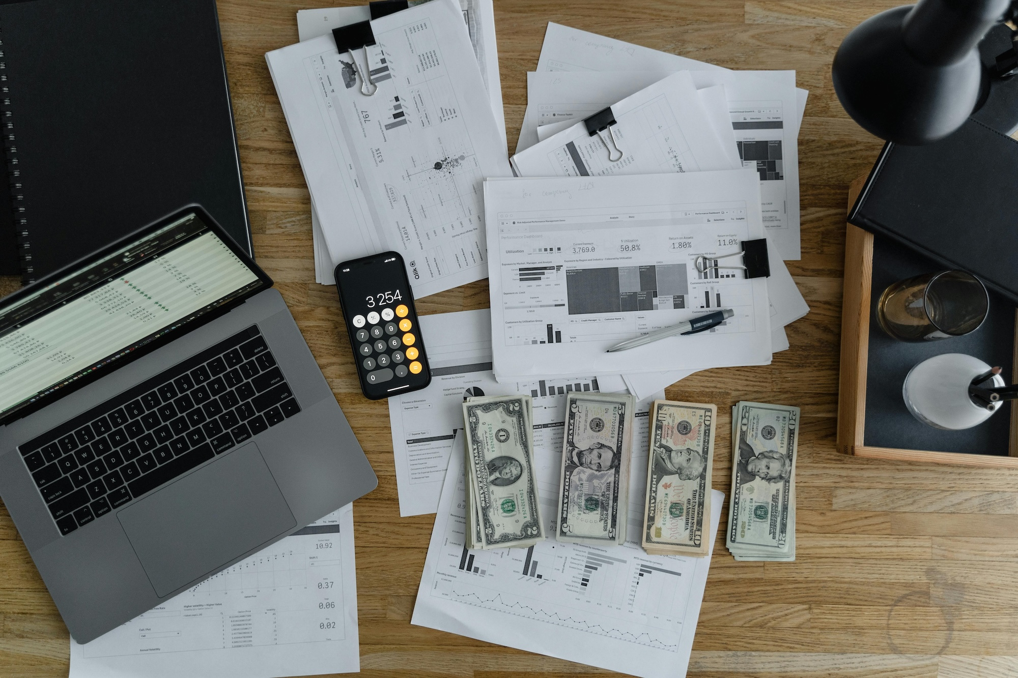 A desk with various papers, tools, and money laid out as a business owner organizes his payroll.