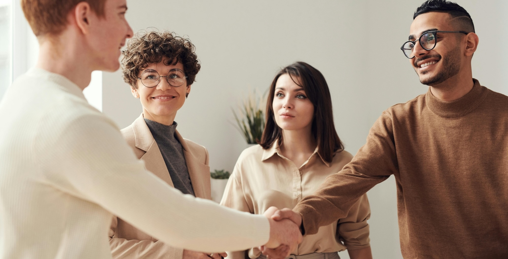 Two men shaking hands as two women look on