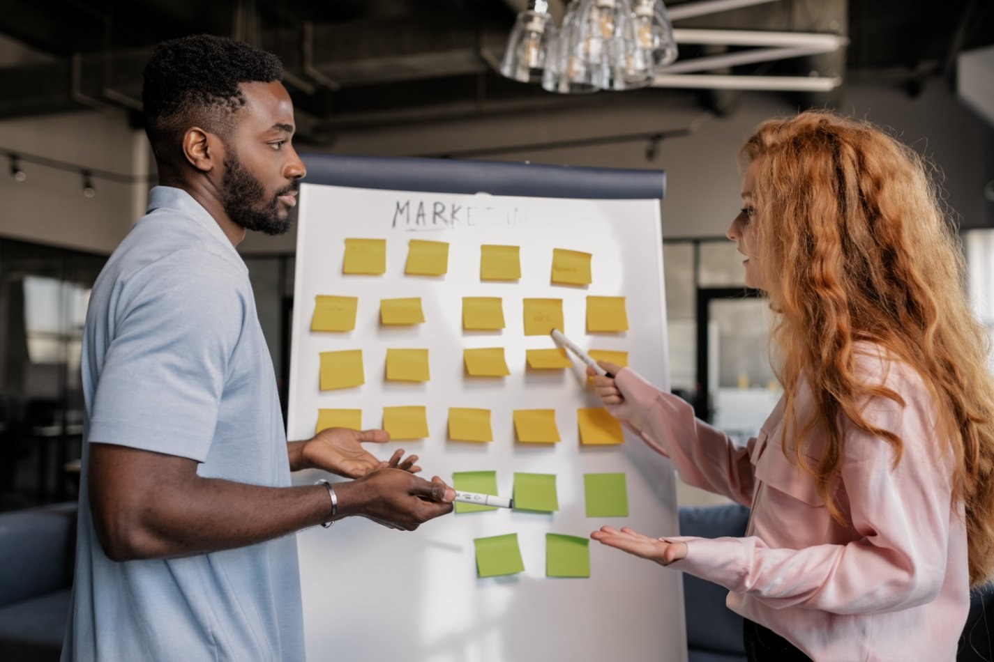 Two people having a conversation with sticky notes on a whiteboard