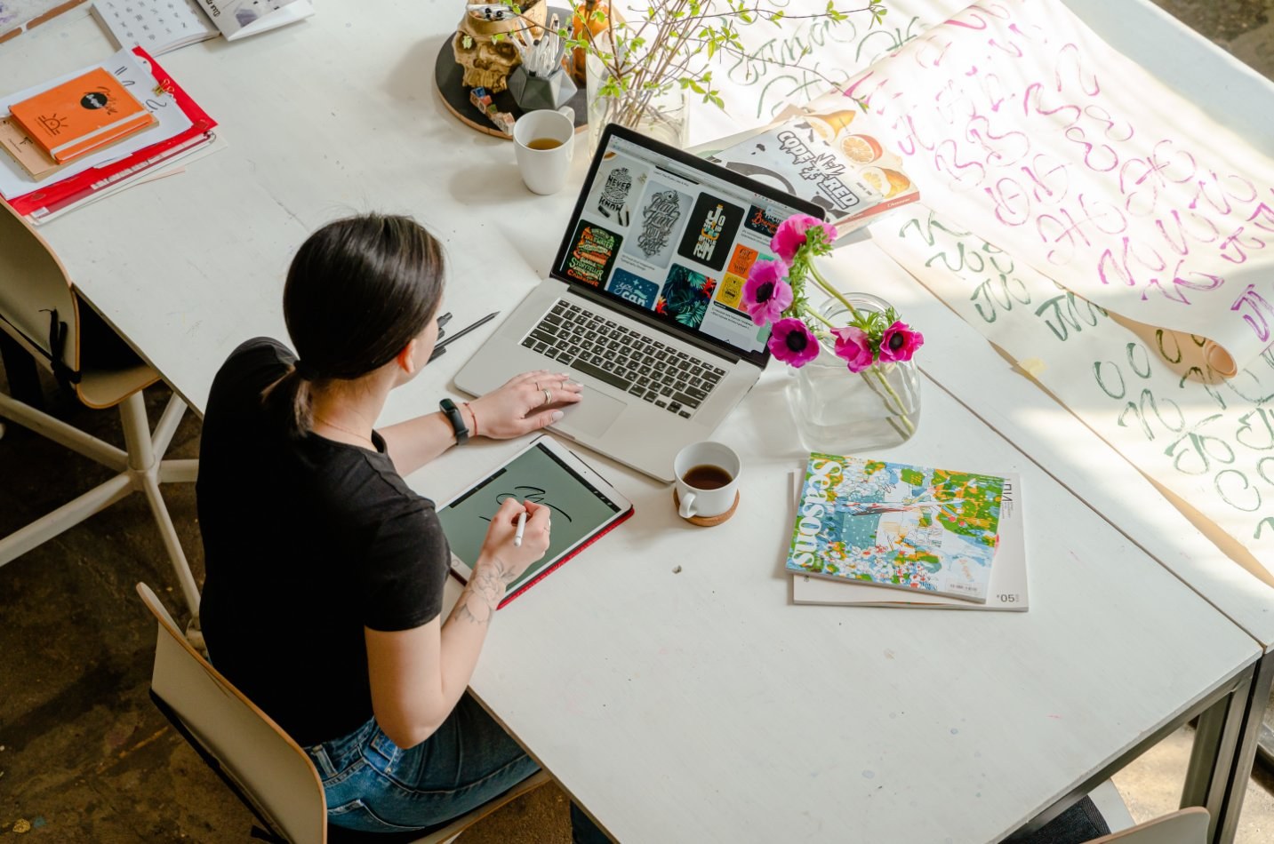 Graphic artist working on table with laptop in front of her