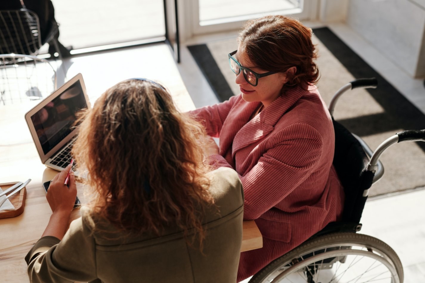 Two women sitting at conference table. Manager utilizing situational leadership with employee one on one.