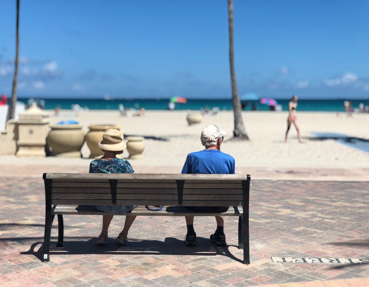 Two people sitting on a bench at the beach