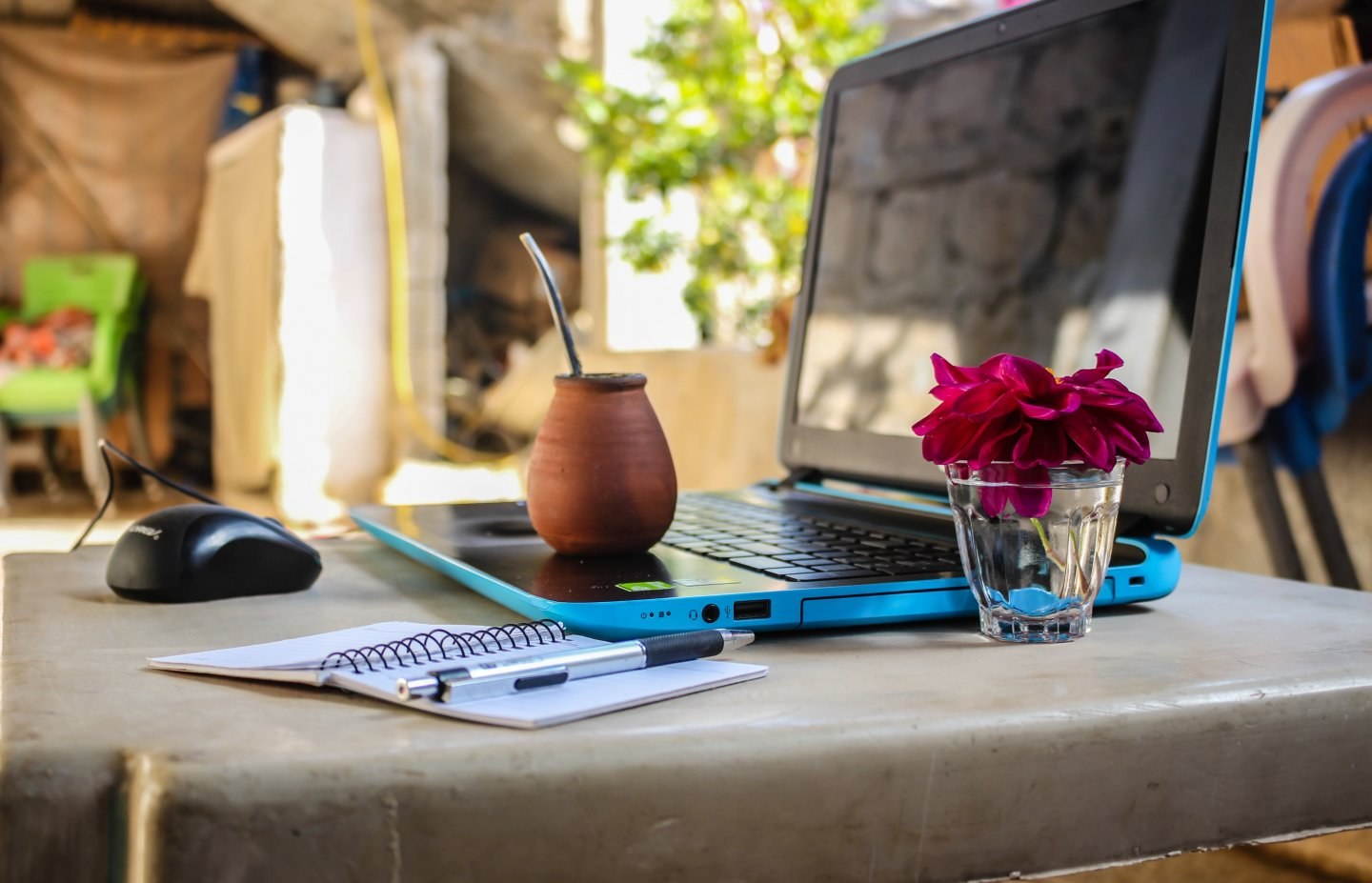 A laptop with a drink and a flower