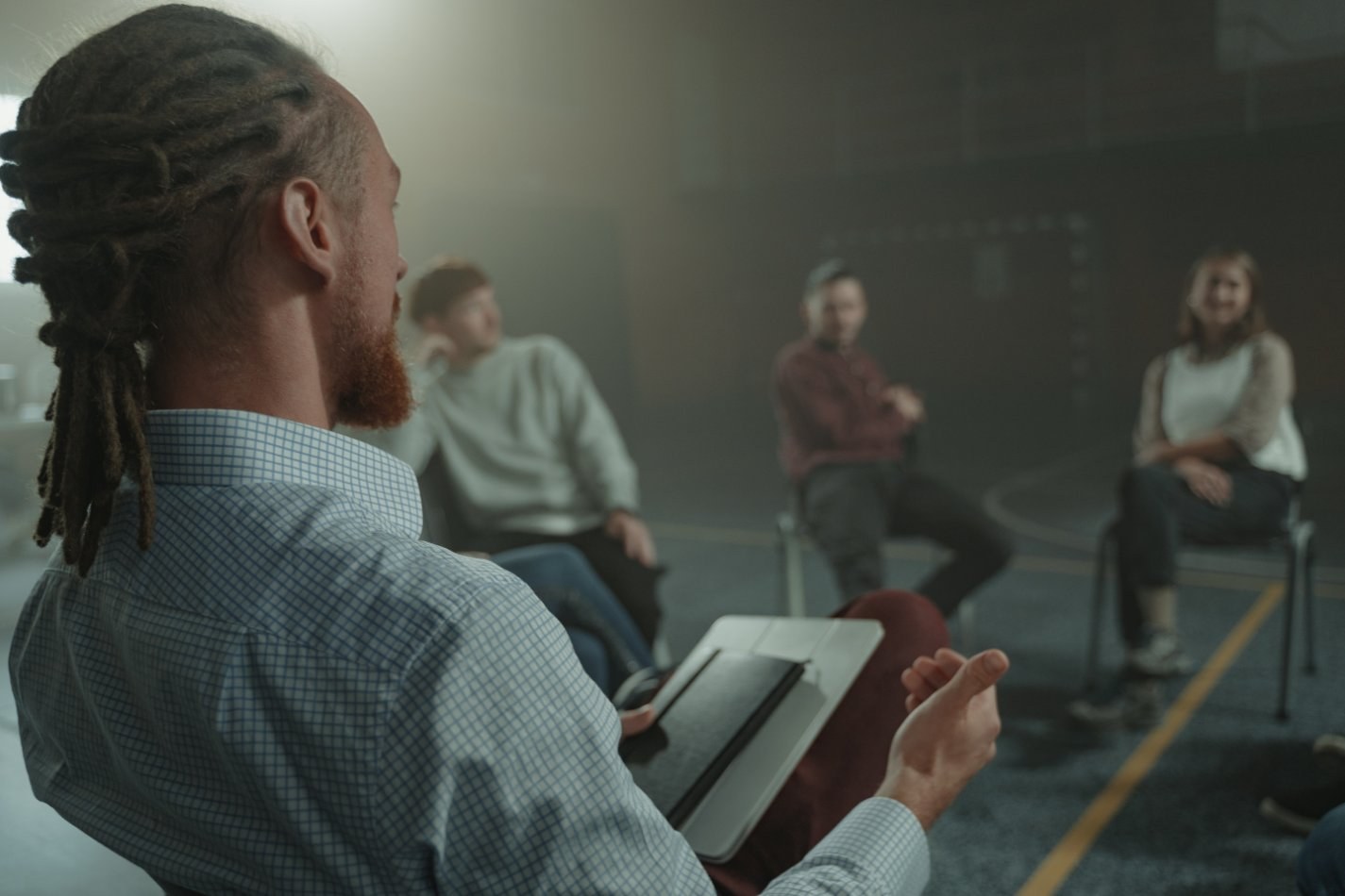 Man speaking to a group of people sitting in a circle