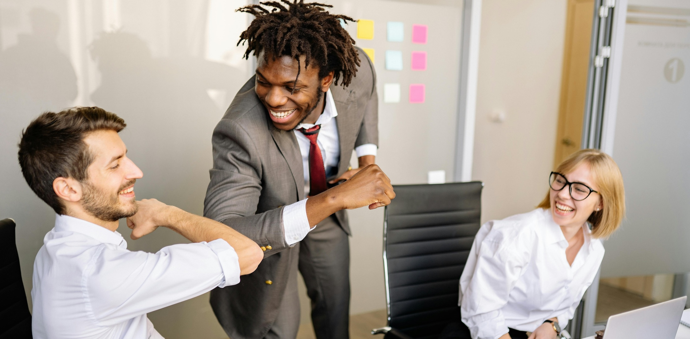 Three co-workers smile with one another in the office.