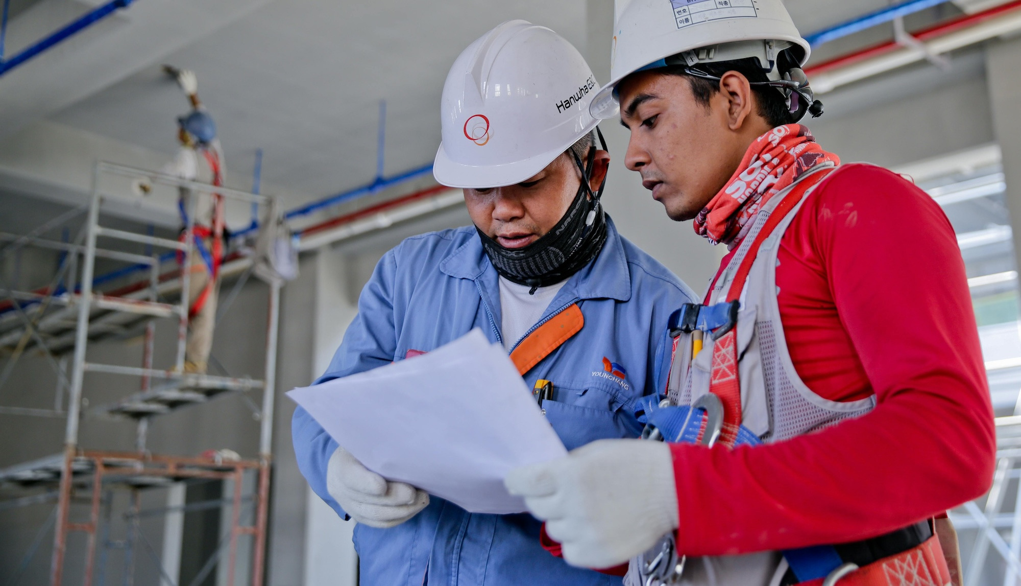 Two construction workers review a document with worksite policies.