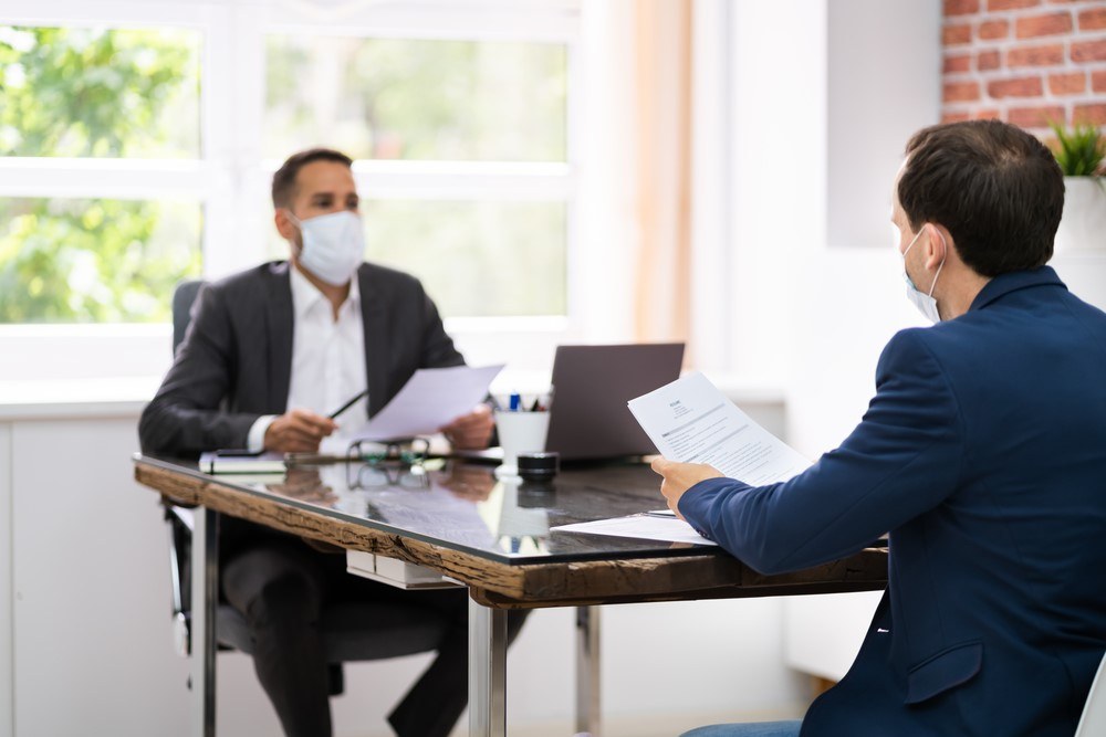 Two people having a conversation at work while wearing masks
