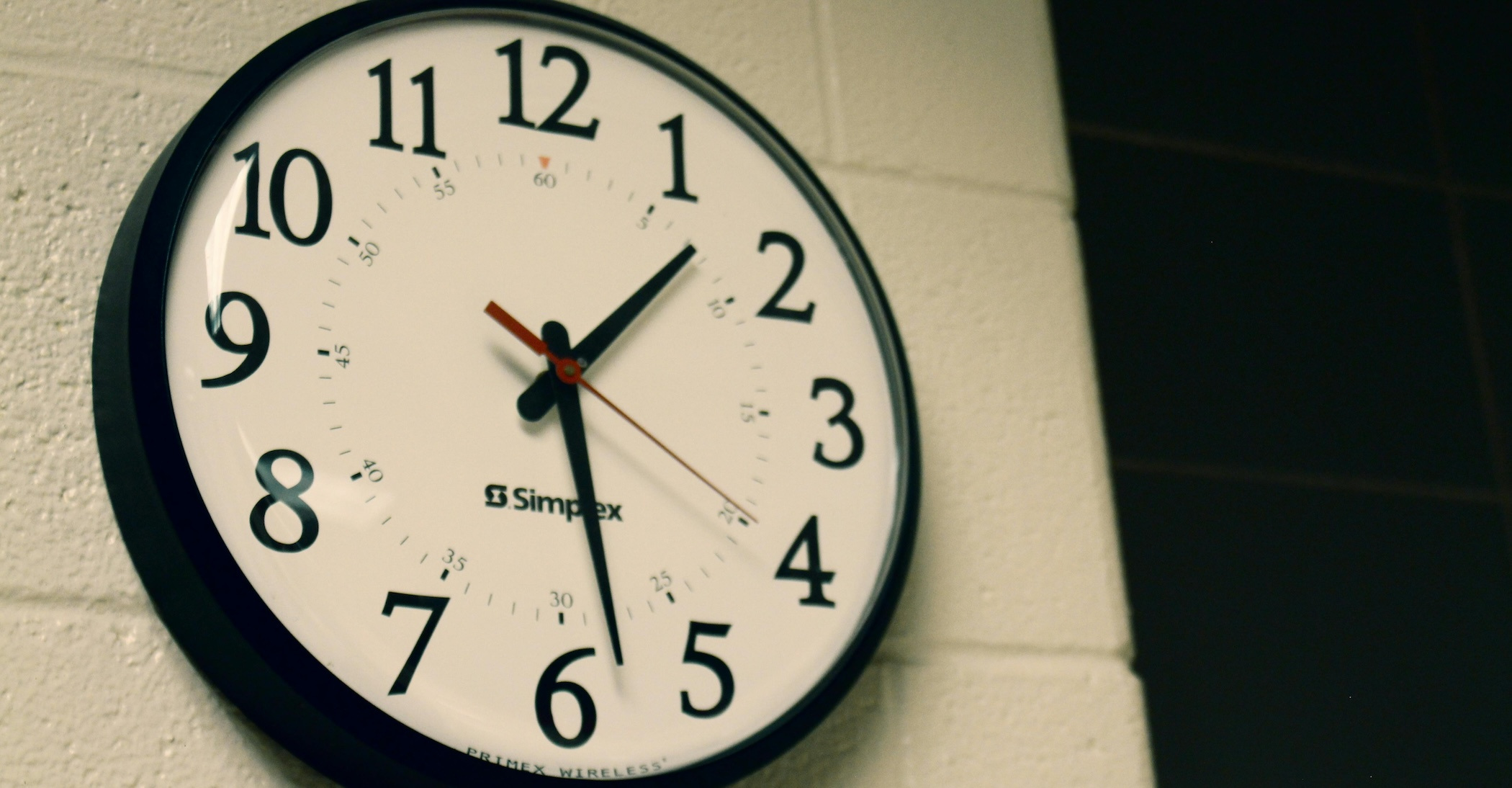 An analog clock on a white painted brick wall