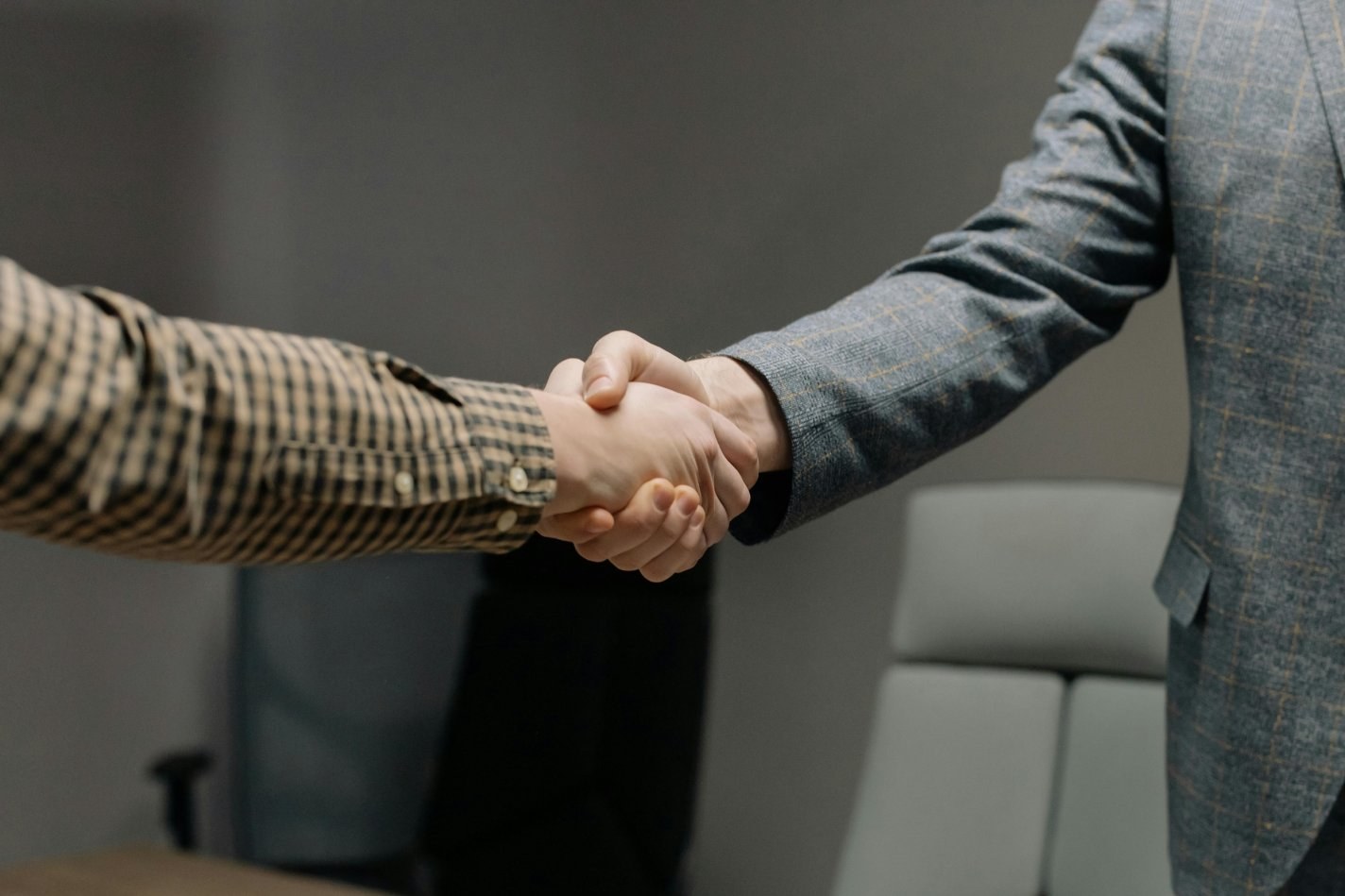 Two men shake hands in an office setting.