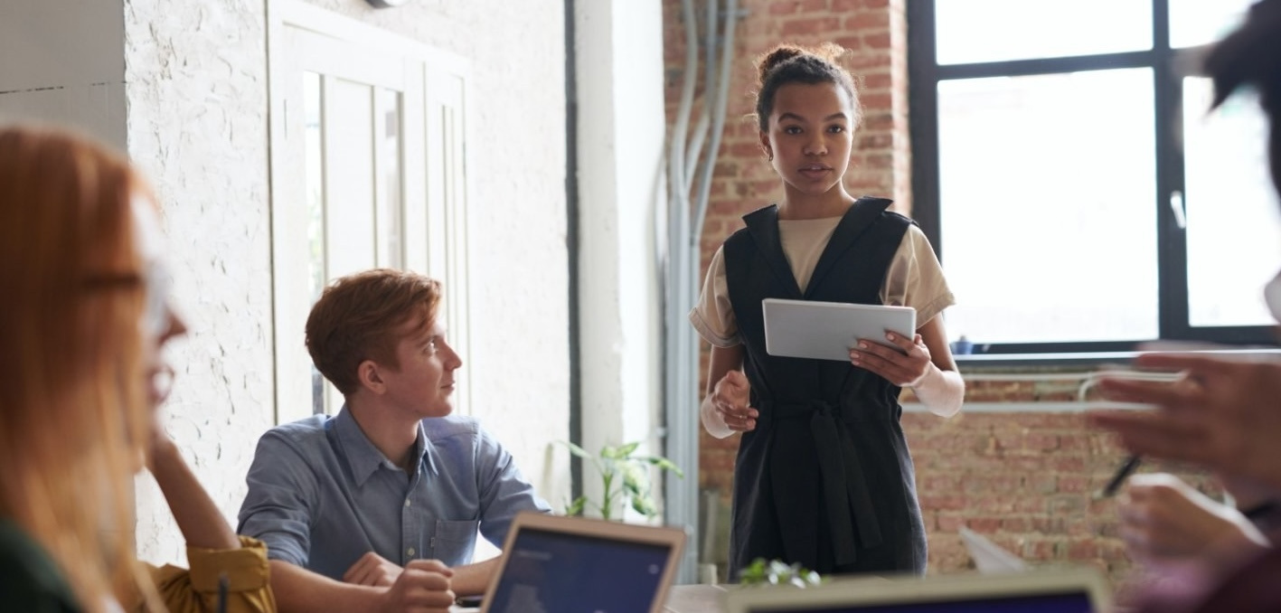 work meeting between coworkers with one woman speaking to the group