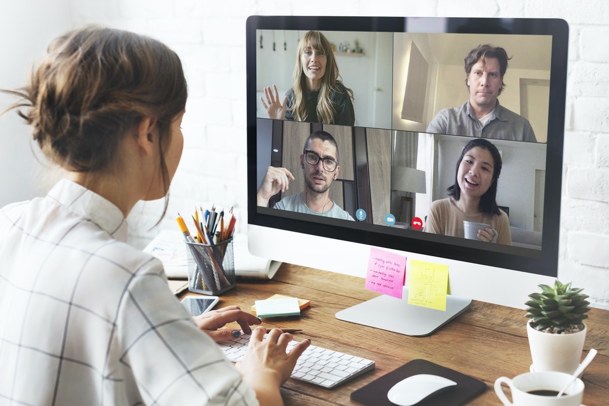 Woman sitting in front of a computer screen with a video call of 4 people talking.